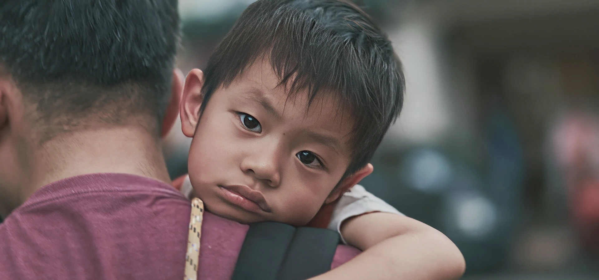 Young child resting on caregiver's shoulder, supported through Karuna's family programs