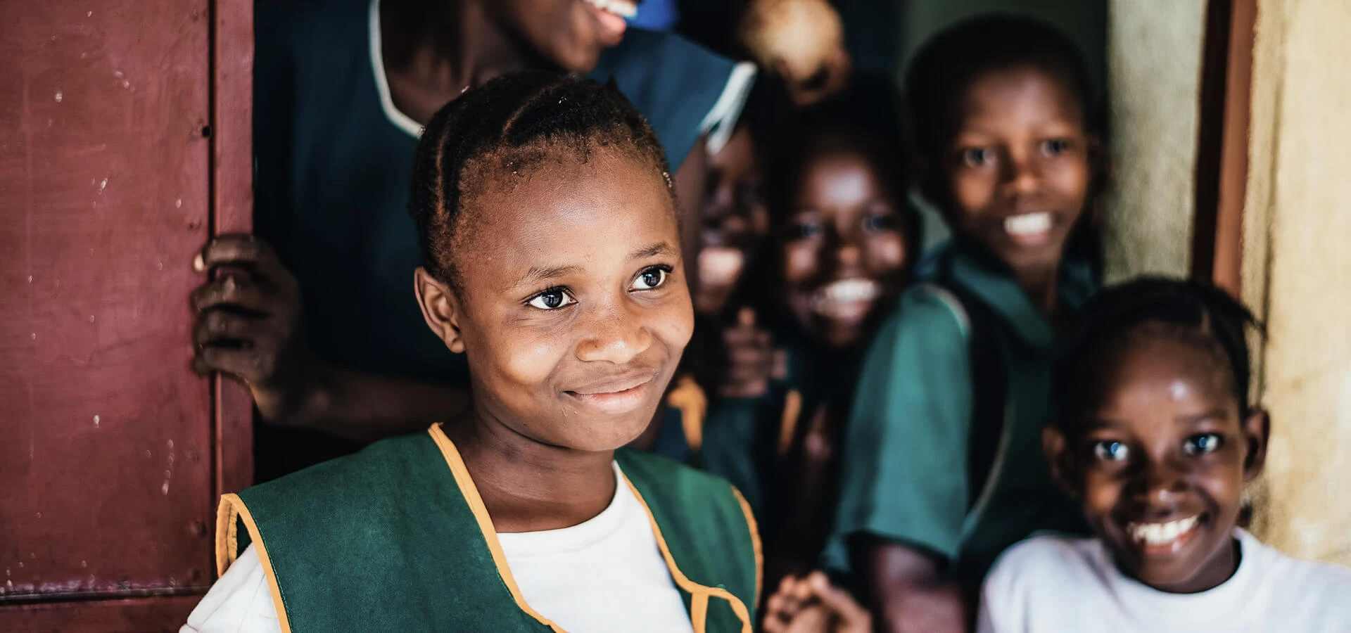 Smiling children in school uniforms, representing Karuna's community development partnerships
