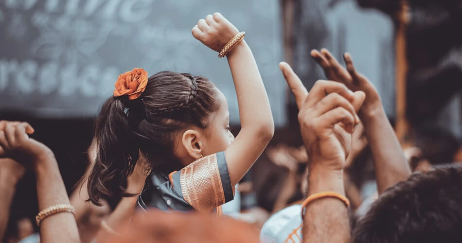 Young girl raising her hand in a crowd during a community classroom event