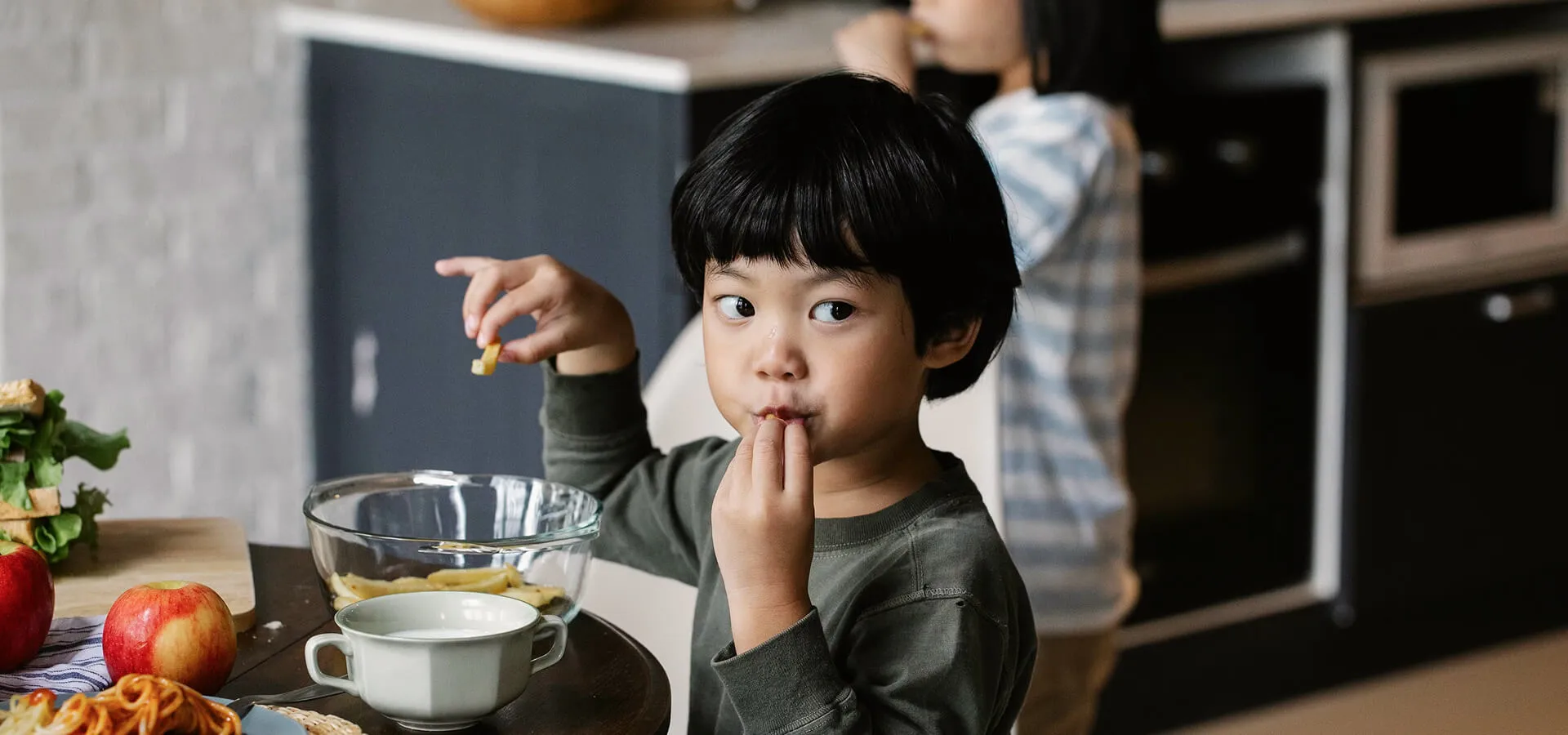 Young child eating a healthy snack in the kitchen, illustrating Karuna's nutrition recovery program