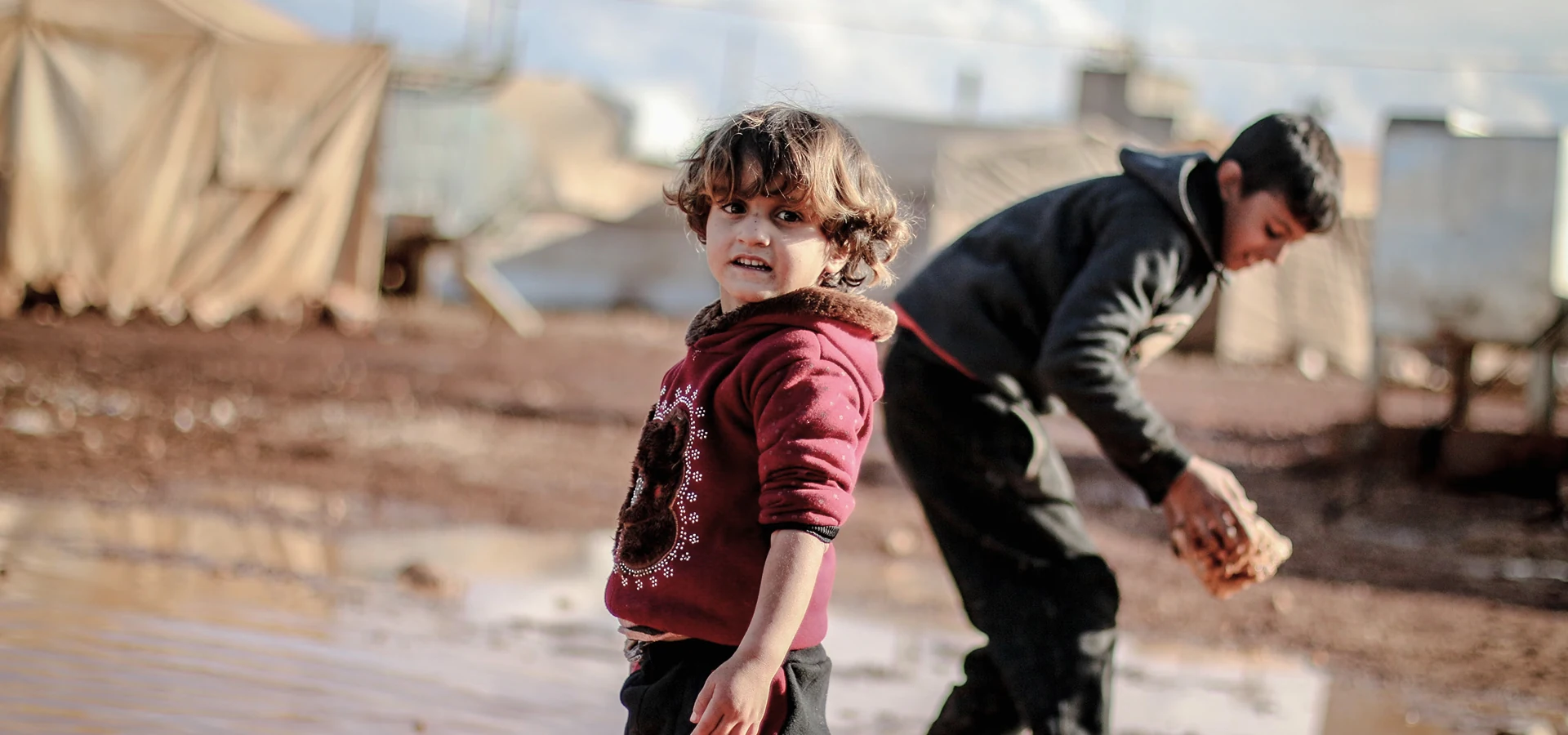 Children playing near tents in a conflict-affected displacement camp