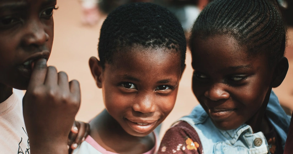 Three young children smiling together outdoors