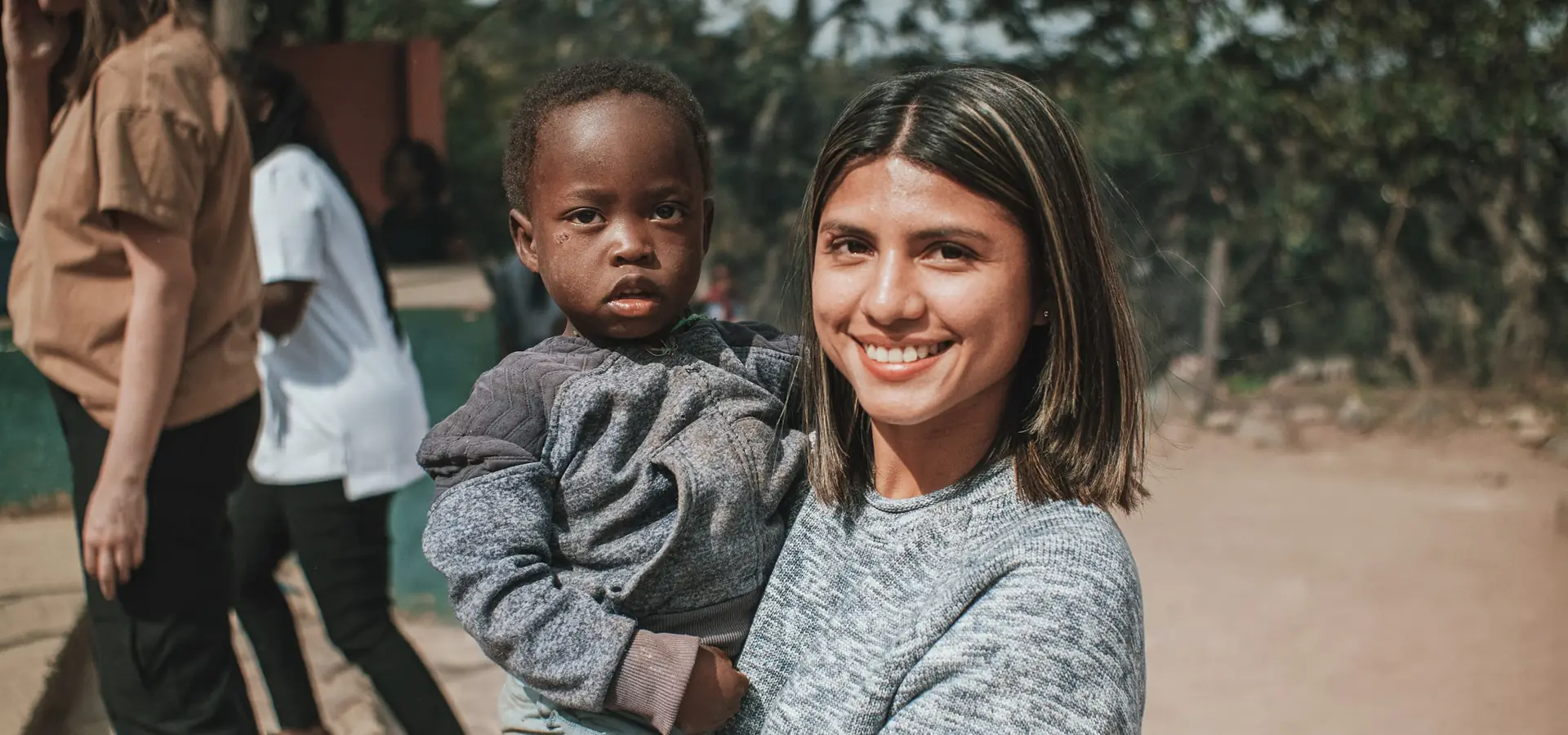 Karuna aid worker holding a young child at a community outreach site