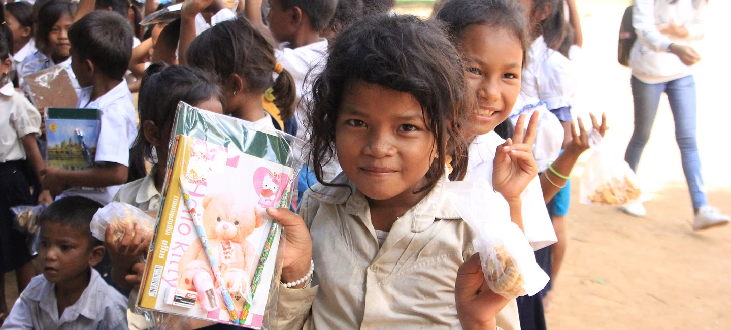 Girls in school uniforms holding new books and school supplies