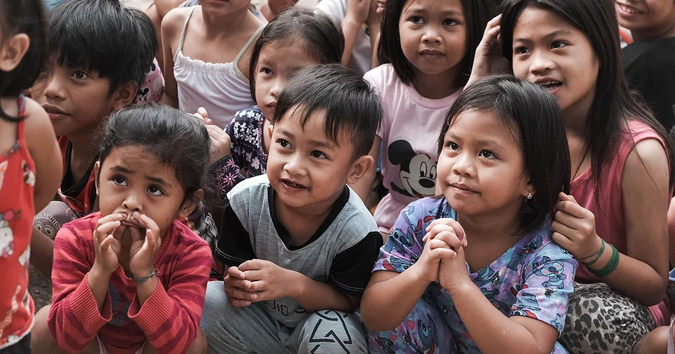 Group of children sitting together, listening attentively at a community event