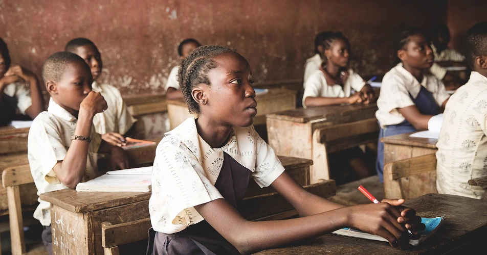 Students in uniforms seated at wooden desks in a reopened classroom