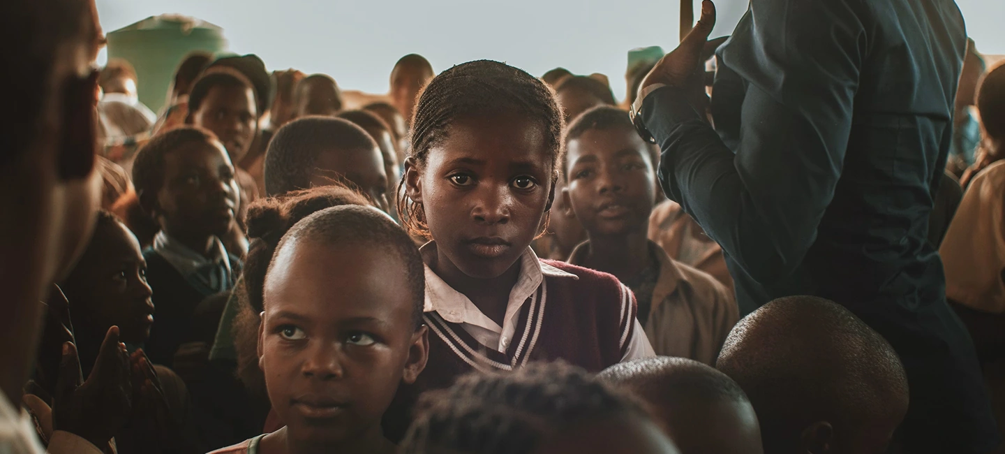 Girl in school uniform standing in a crowd during book distribution