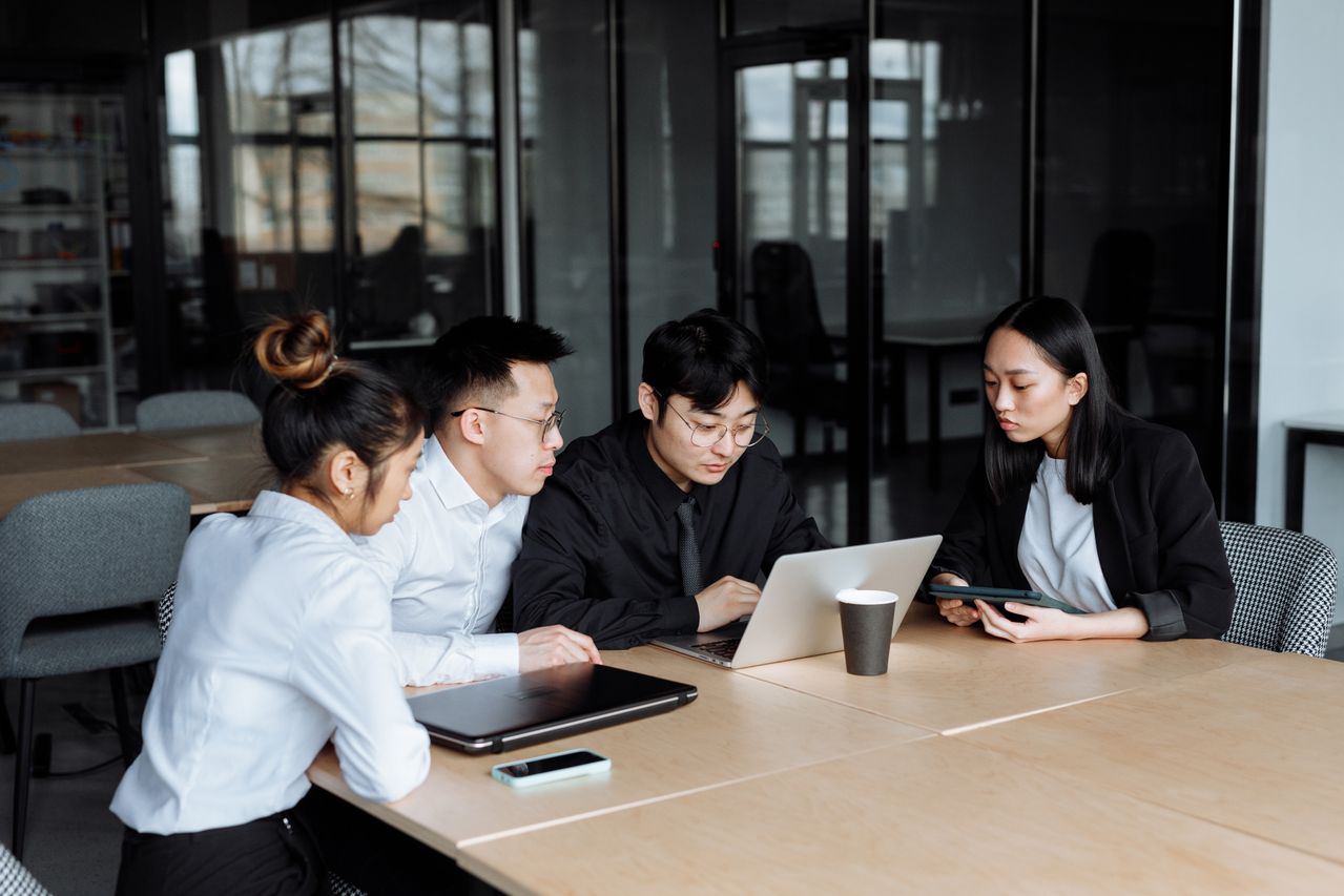 Four young professionals sitting around a table working together with laptops and a tablet.