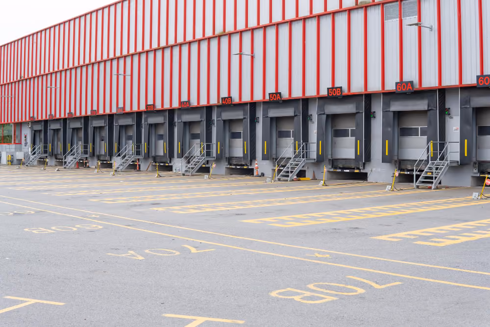 White box truck backed up to a warehouse loading dock with pallets inside.