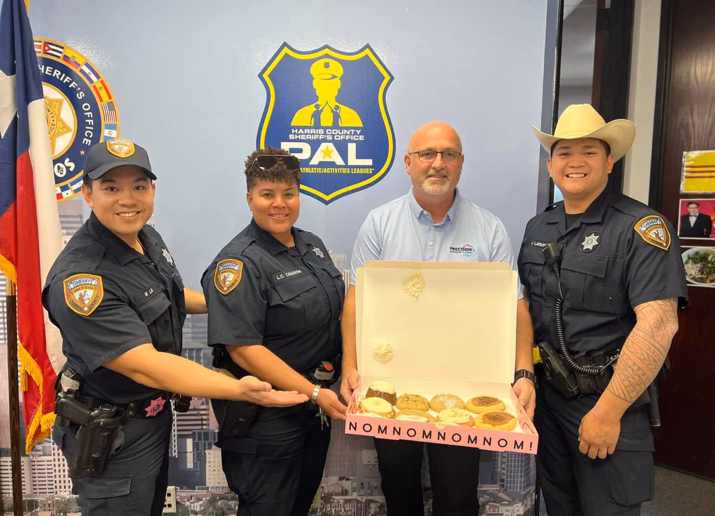 Three sheriff officers and a man holding a box of assorted cookies with 'NOMNOMNOMNOM!' text.