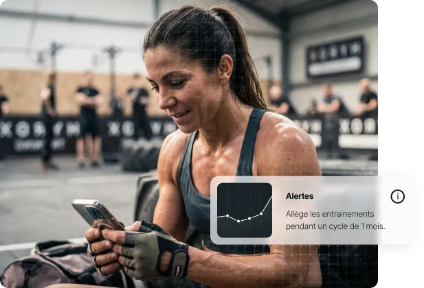 Femme sportive en tenue de sport consulte son téléphone dans une salle de sport.