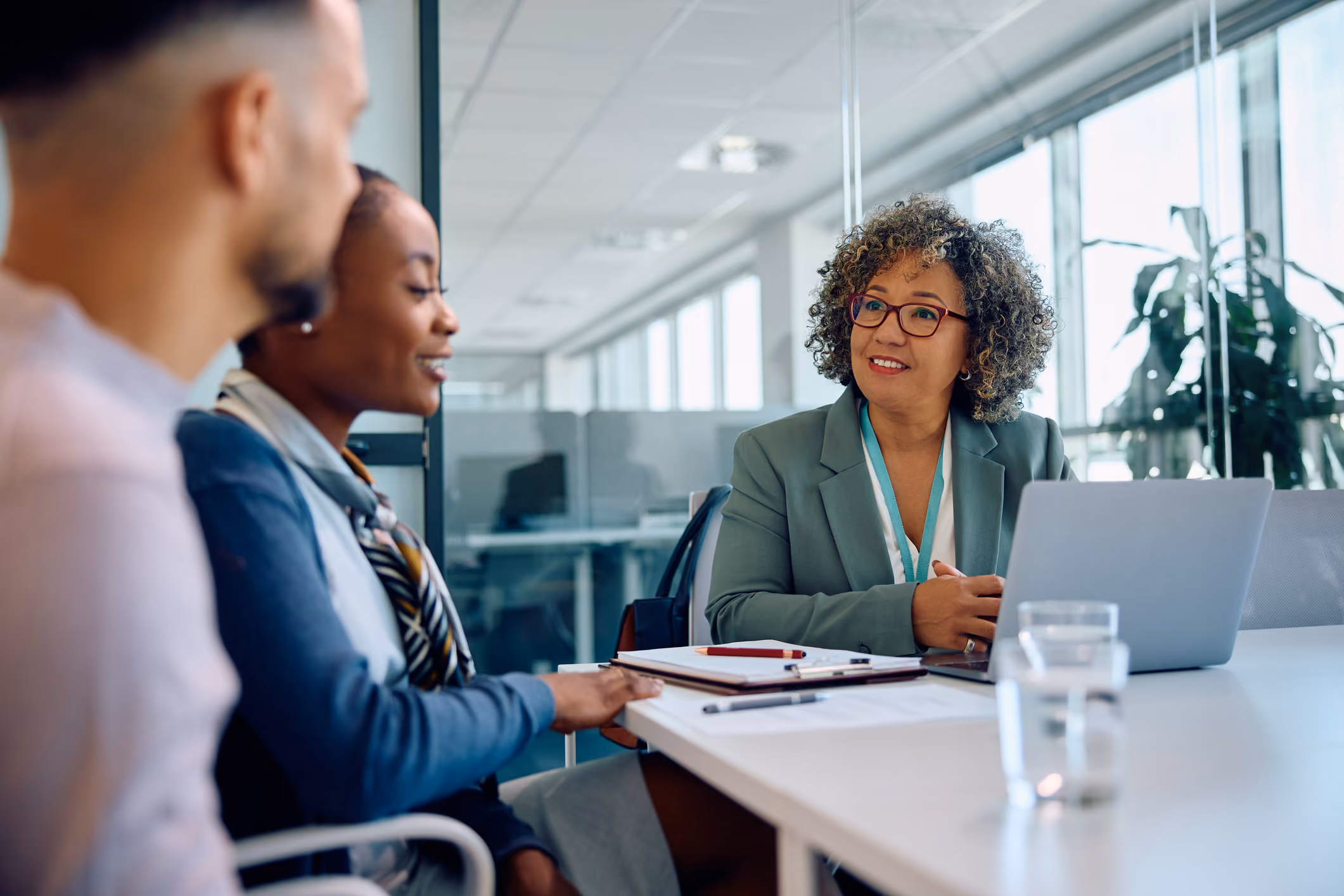 Three diverse professionals having a meeting in a bright office with a laptop and documents on the table.