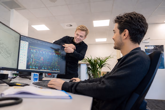 Twee collega's van werkvoorbereiding en calculatie overleggen achter hun schermen