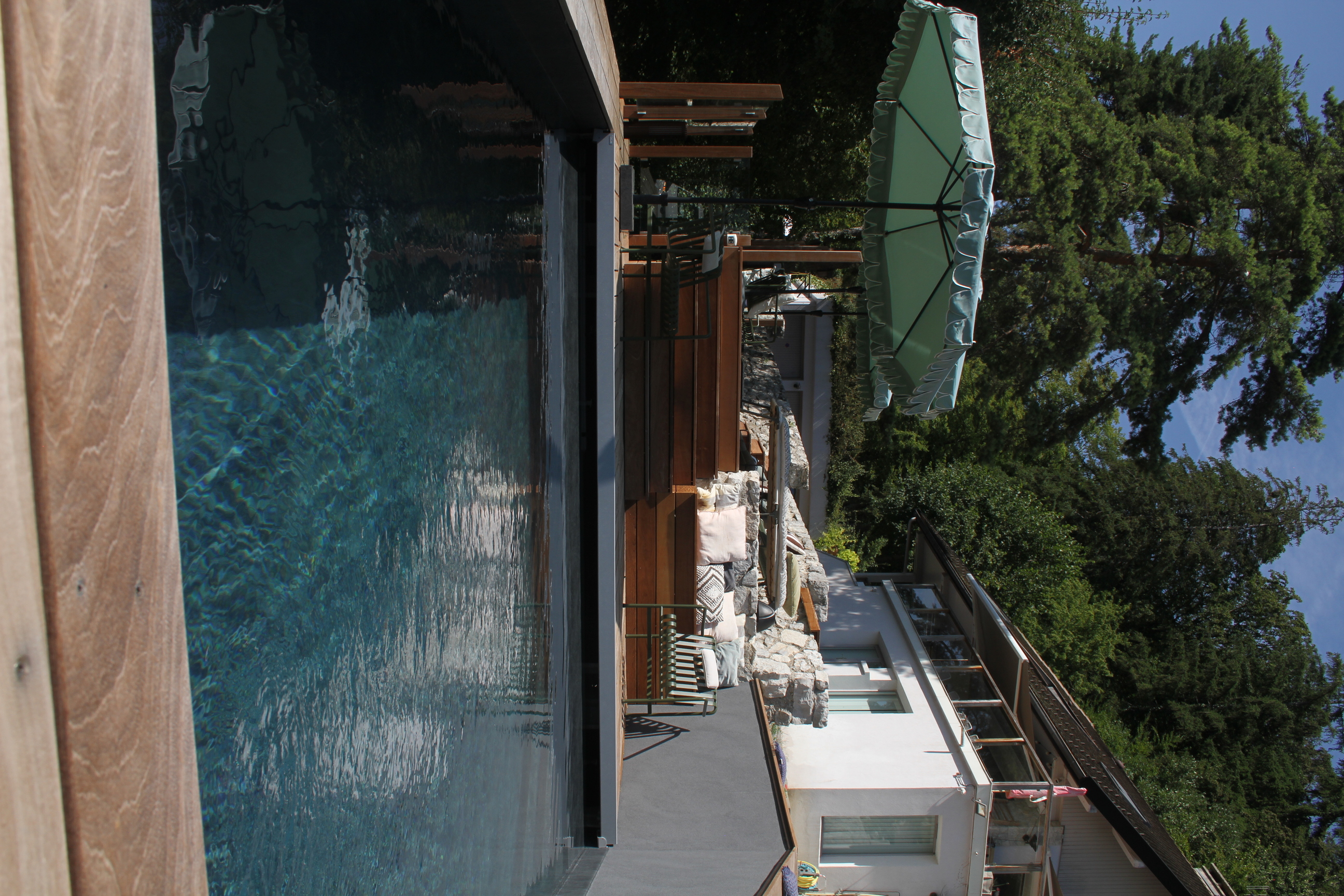 Gros plan sur une piscine avec terrasse en bois et parasol.