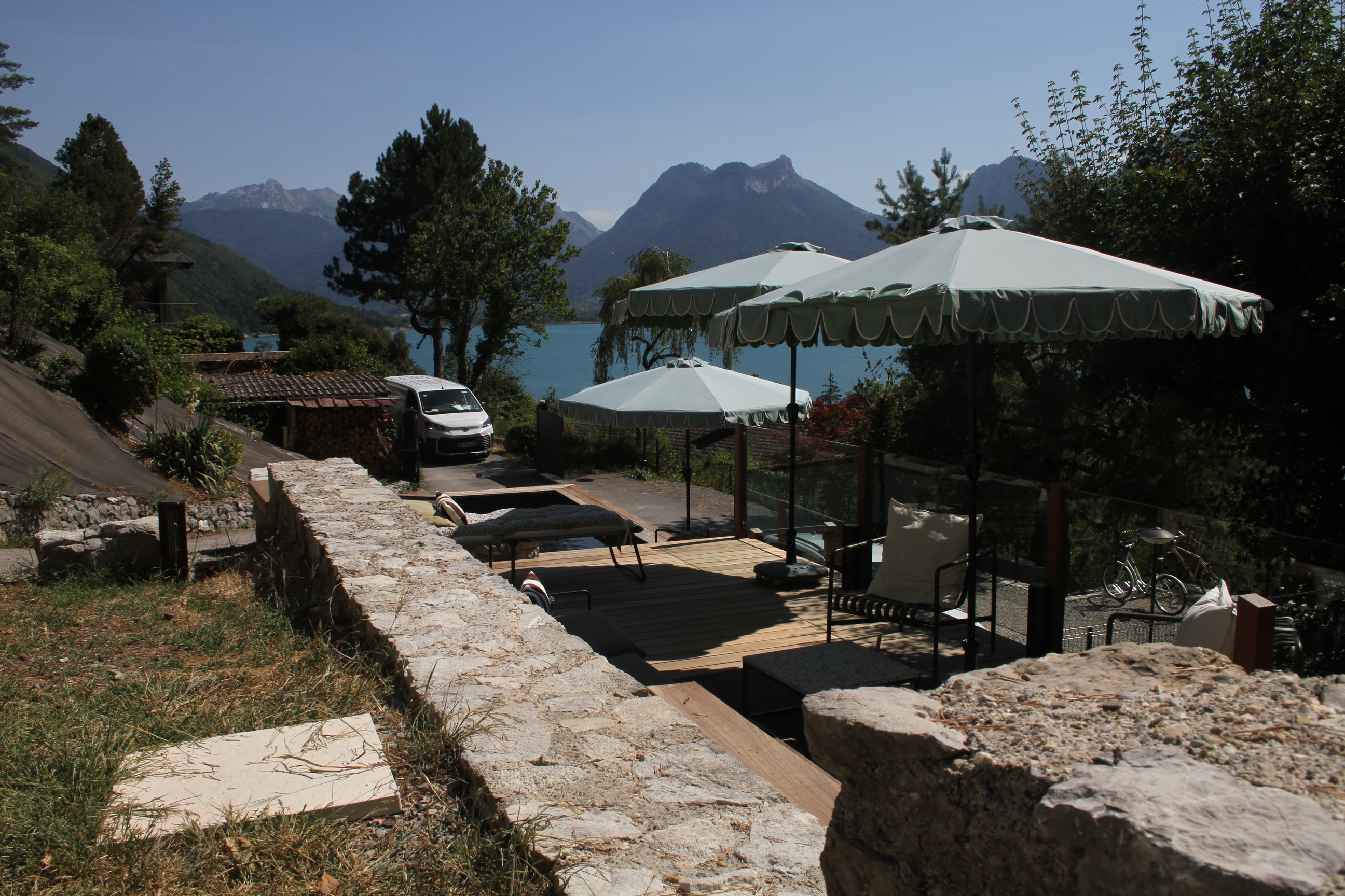 Vue plongeante sur une piscine à la forme trapézoïdale sur mesure et sa terrasse en bois.