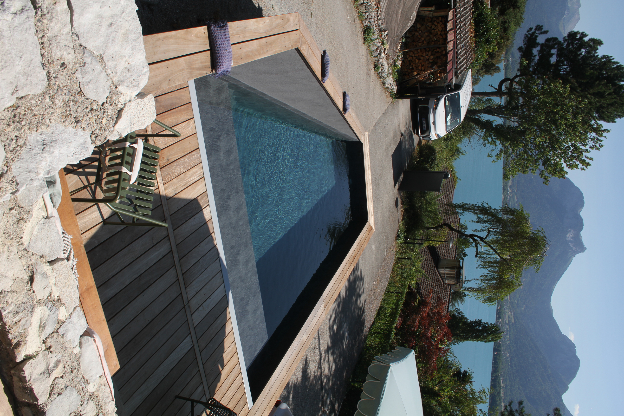 Vue d'ensemble d'une piscine avec habillage en acier corten devant une maison contemporaine.