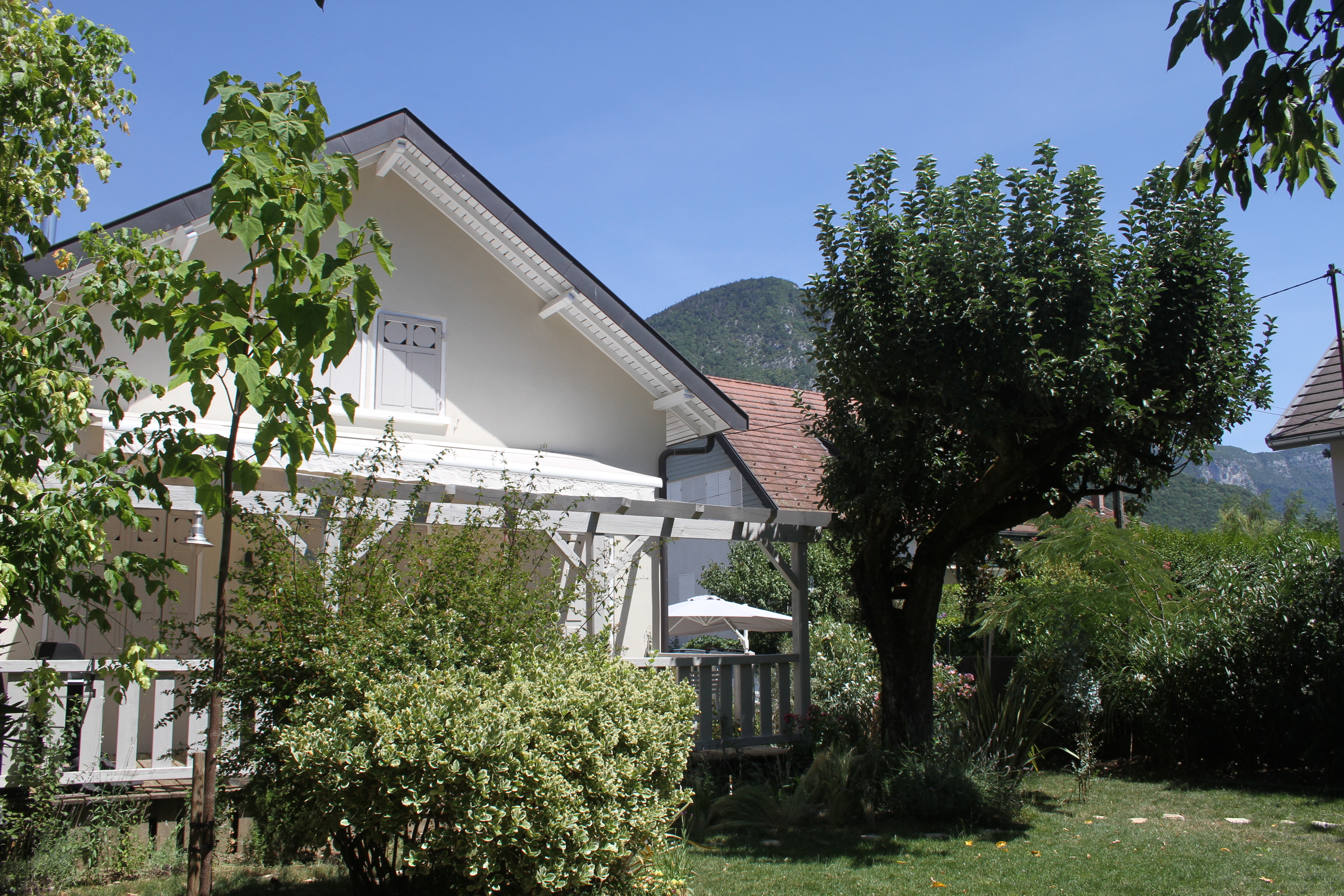 Terrasse paysagée avec mur en pierre et vue panoramique sur le lac et les montagnes.