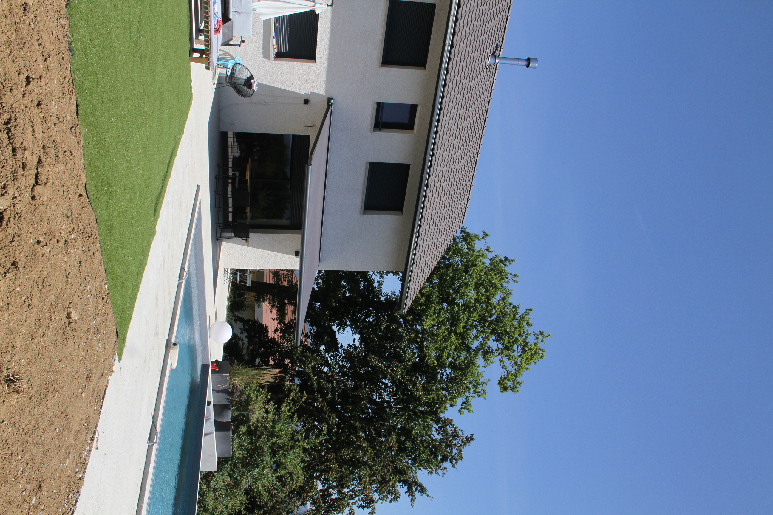 Vue d'ensemble de la façade de maison avec piscine creusée et espace terrasse.