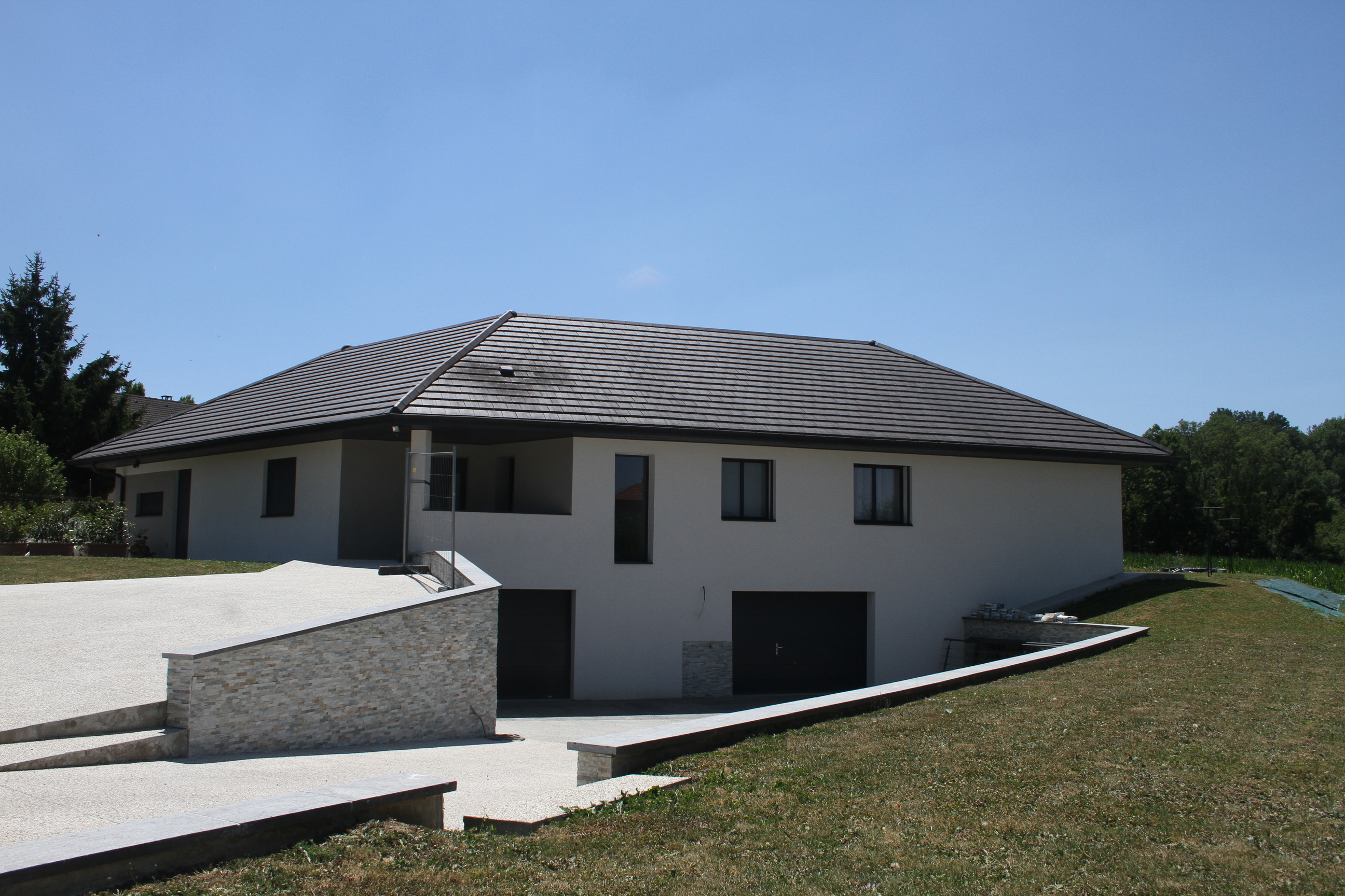 Façade de maison contemporaine avec muret en parement de pierre naturelle.