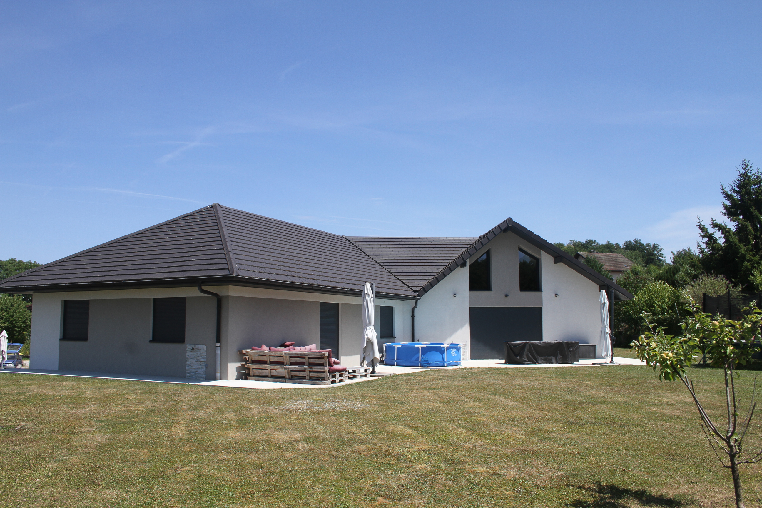 Vue du jardin et de la façade arrière de la maison avec salon de jardin en palettes.
