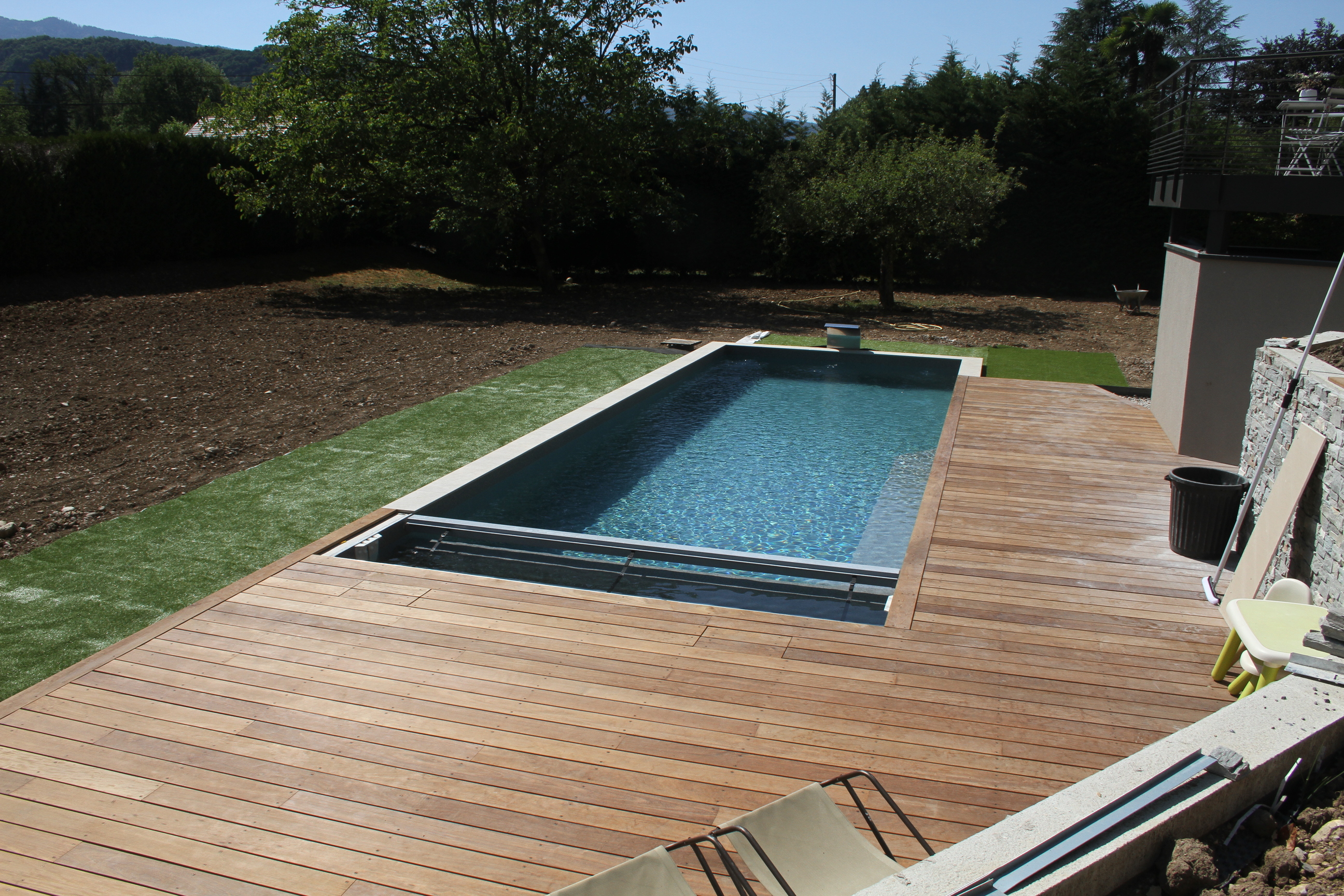 Vue panoramique en hauteur de la piscine, de la terrasse en bois et du jardin.