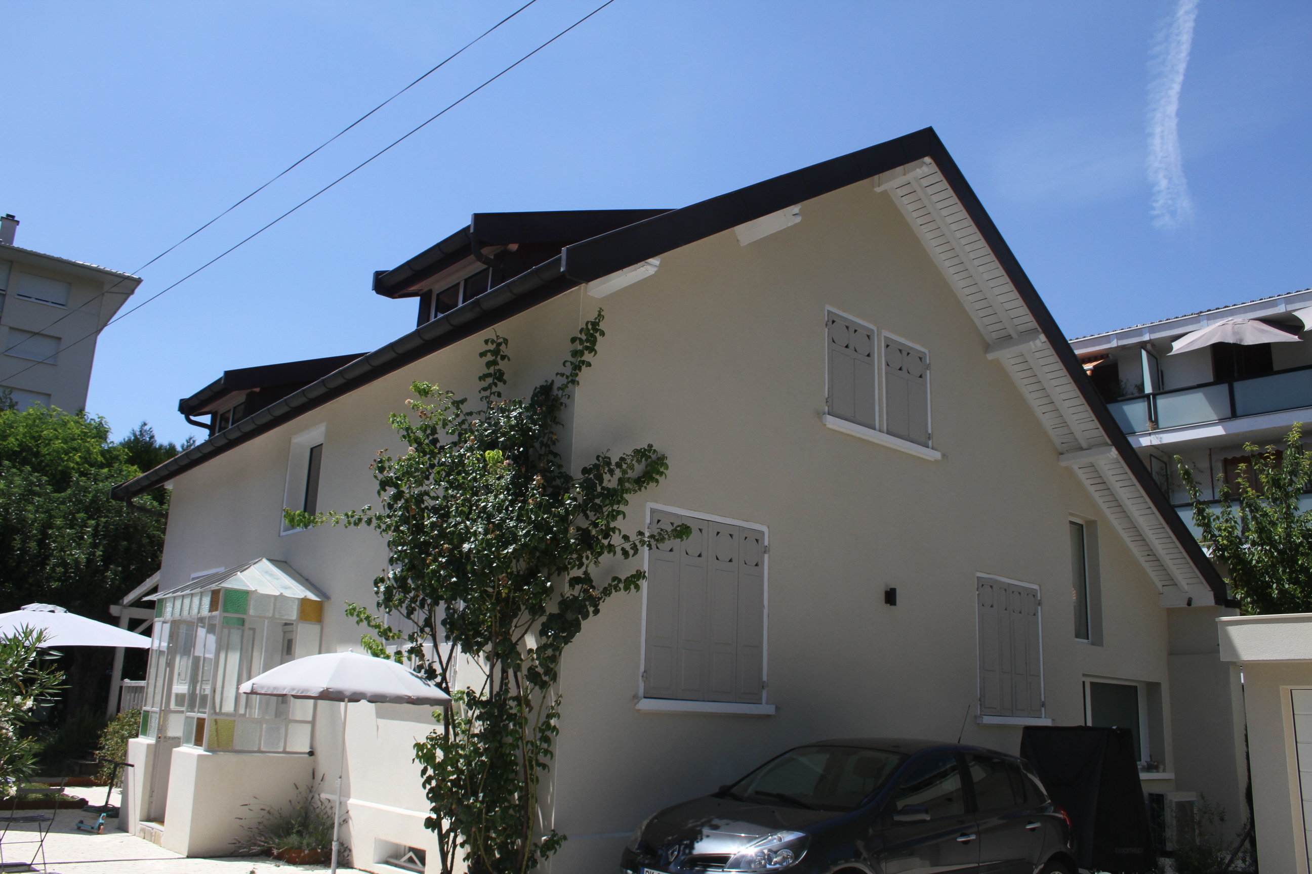 Façade de maison individuelle avec volets battants en bois et véranda.