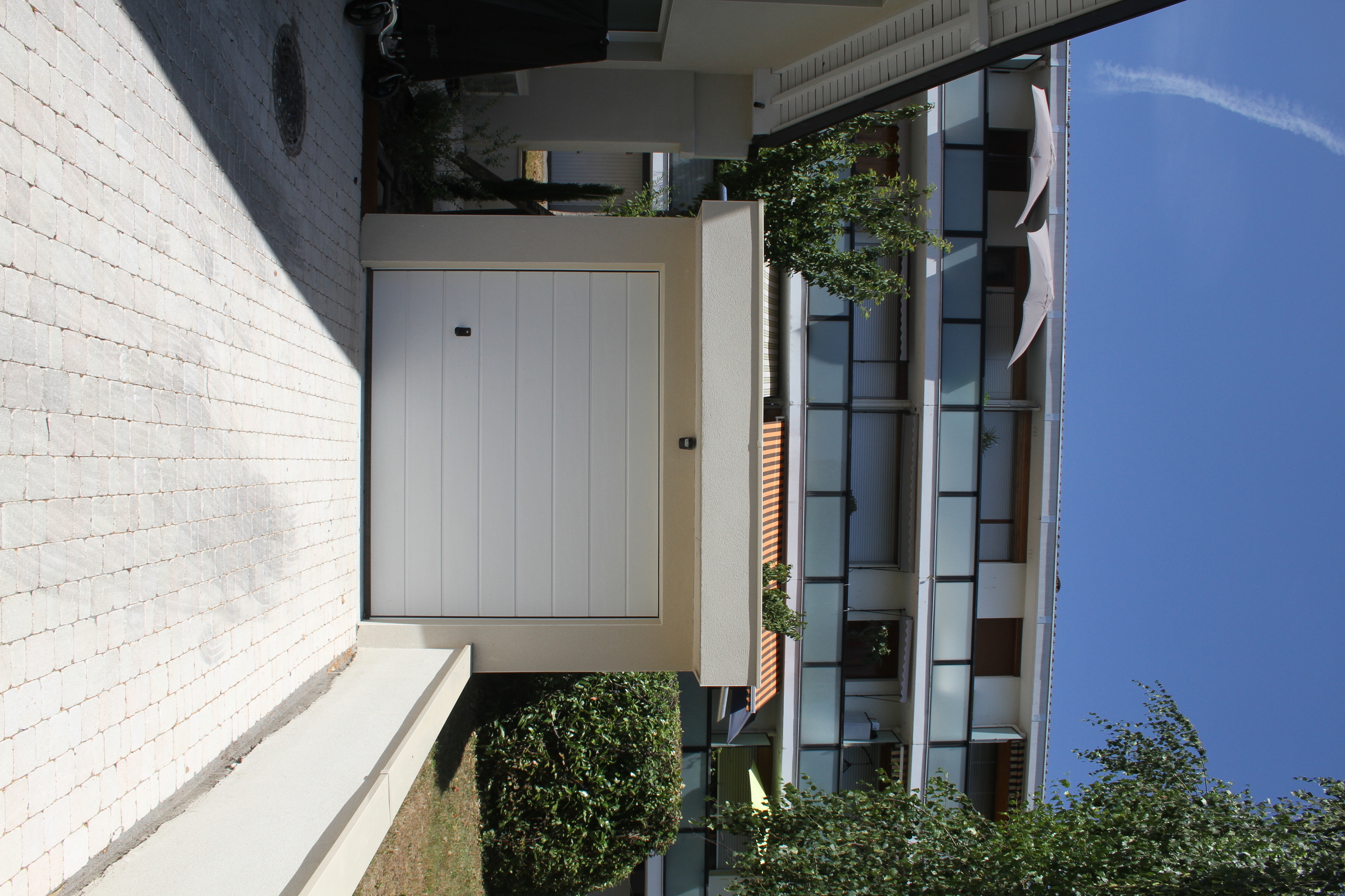 Garage indépendant avec porte sectionnelle blanche et allée pavée.