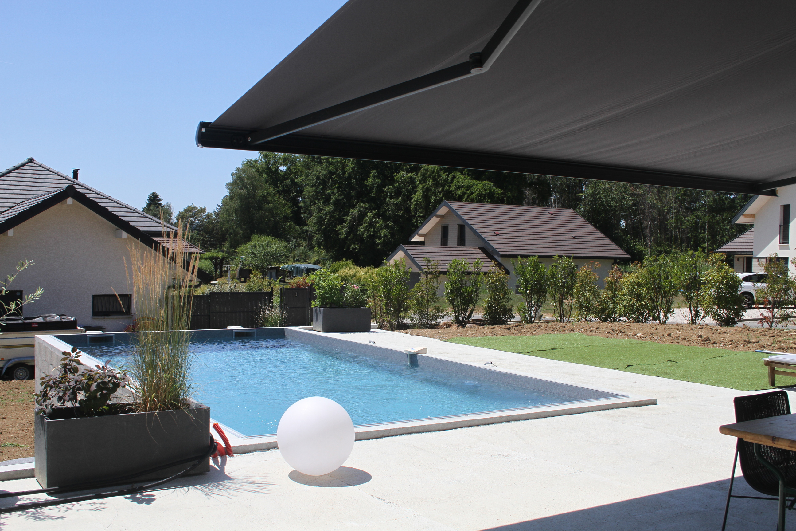 Espace terrasse et piscine ombragé par un grand store banne rétractable.
