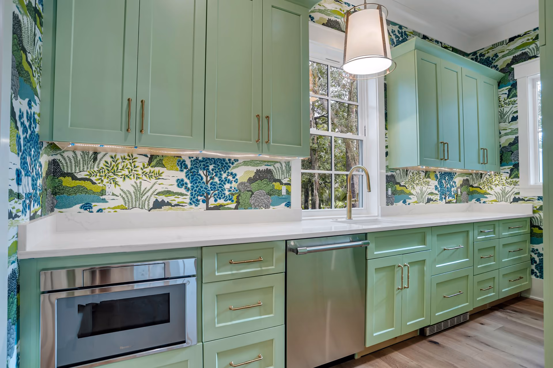 Bright modern kitchen with white cabinets, stainless steel appliances, and light wood flooring.