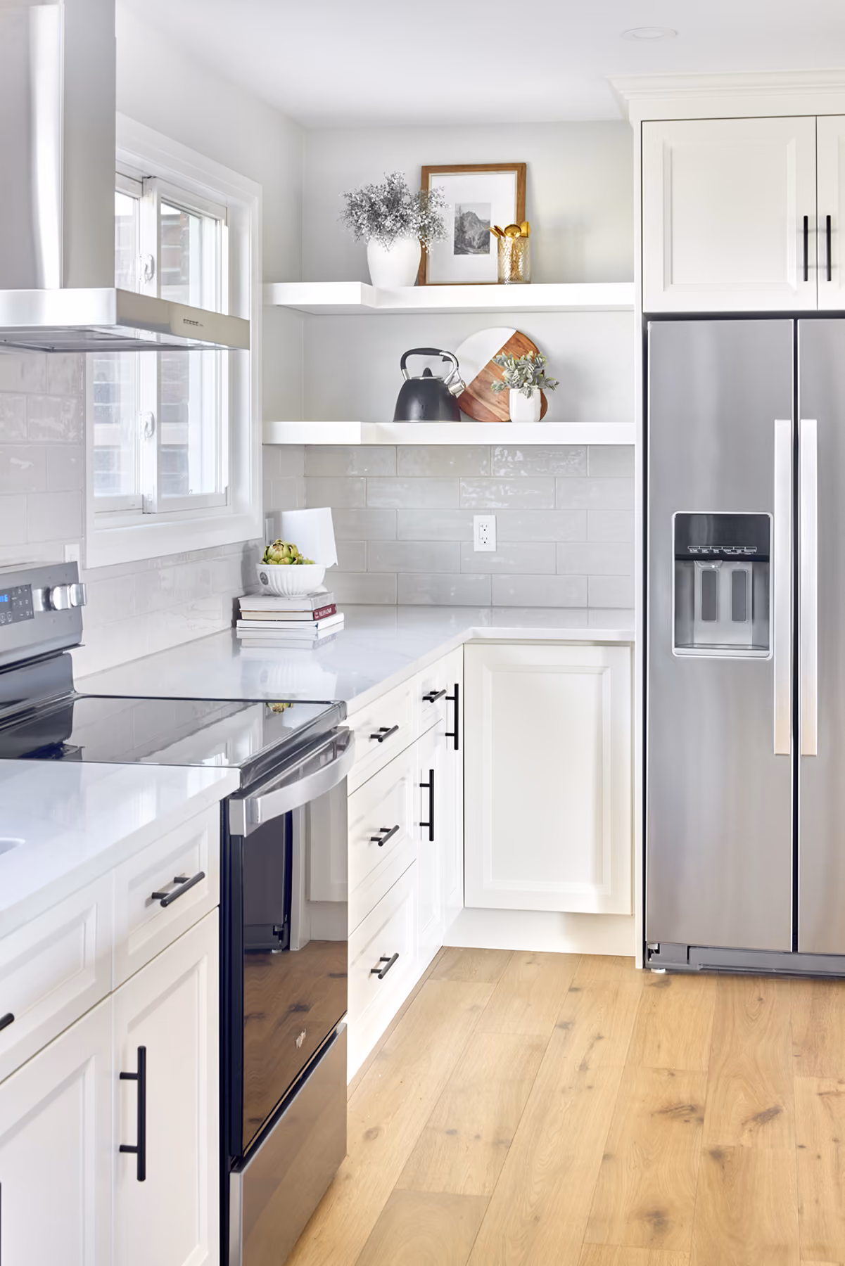 Bright modern kitchen with white cabinets, stainless steel appliances, and light wood flooring.