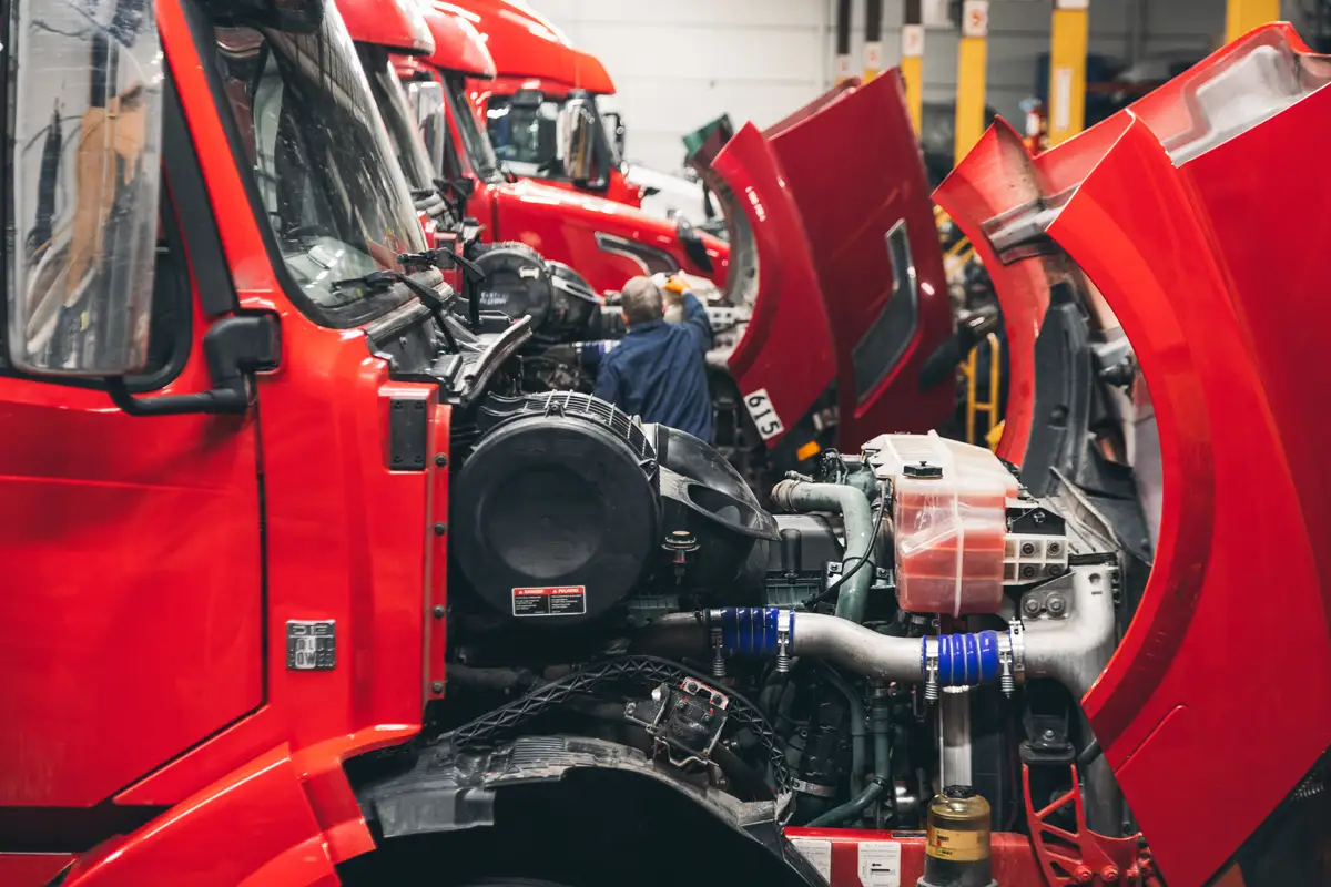 Diesel mechanic working on red semi truck