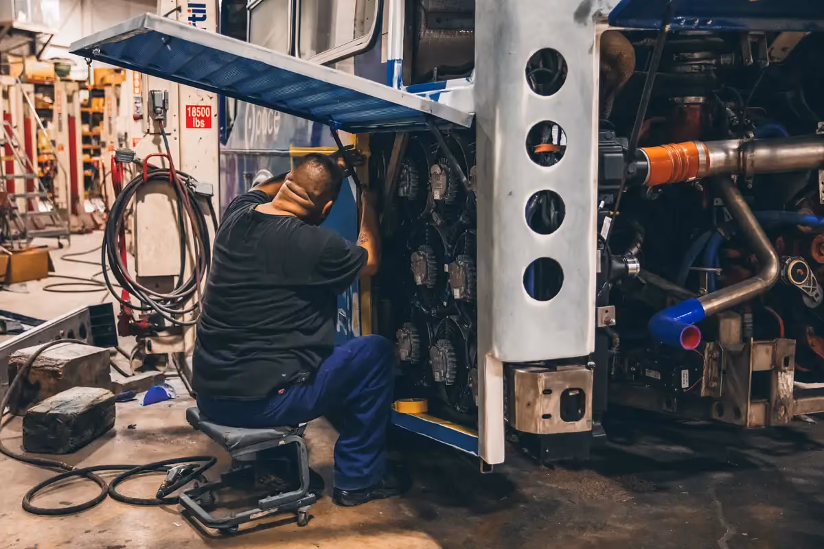 Diesel mechanic performing bus repair services
