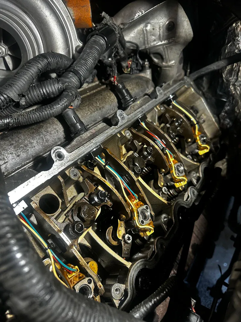 Heavy-duty engine repair showing exposed rocker arms, wiring and turbocharger components inside a diesel truck engine.