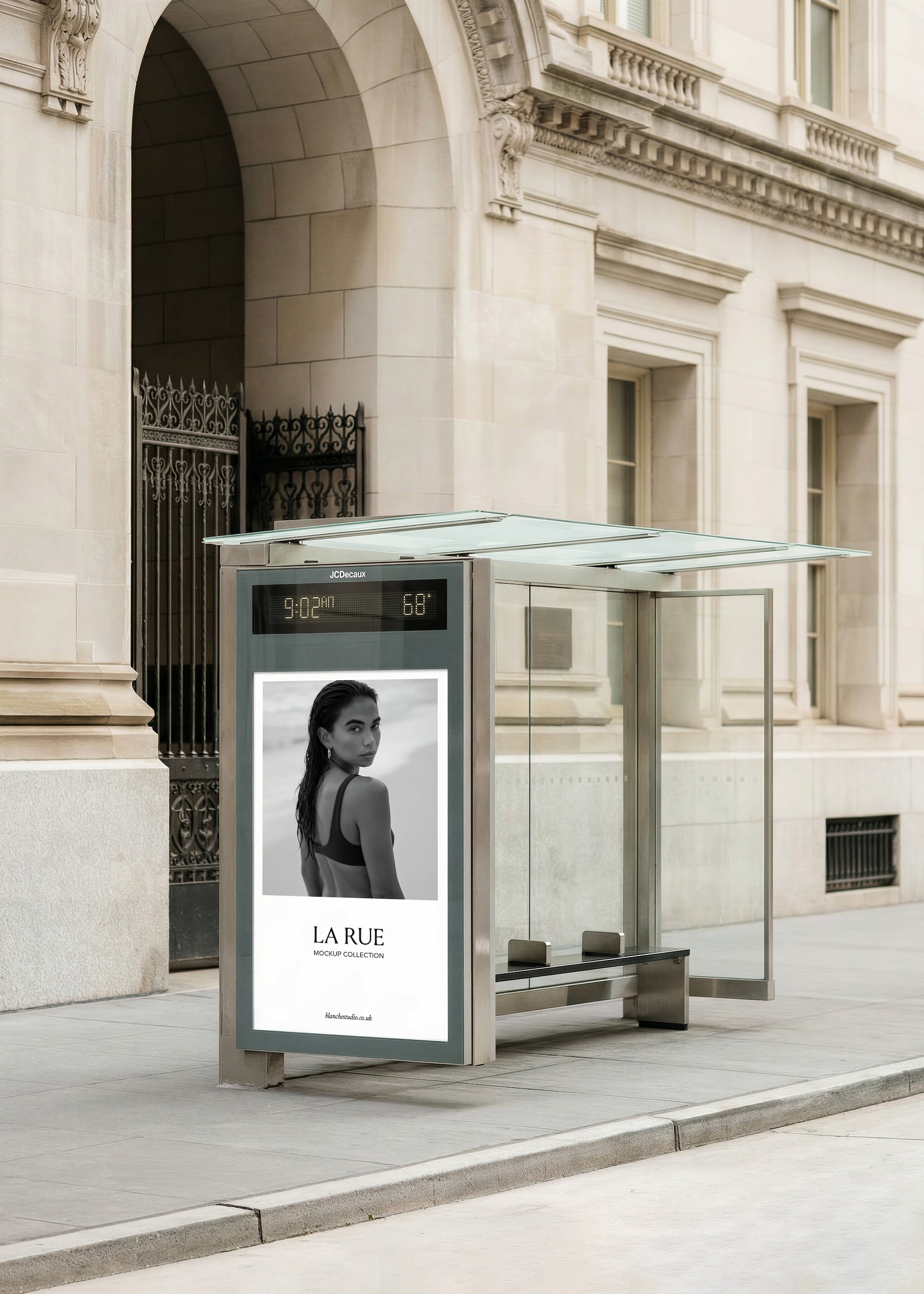 Modern glass and metal bus shelter mockup on a city street with a digital display showing 9:02 AM and 68°F, featuring a black and white fashion advertisement of a woman with the text 'LA RUE MOCKUP COLLECTION'.