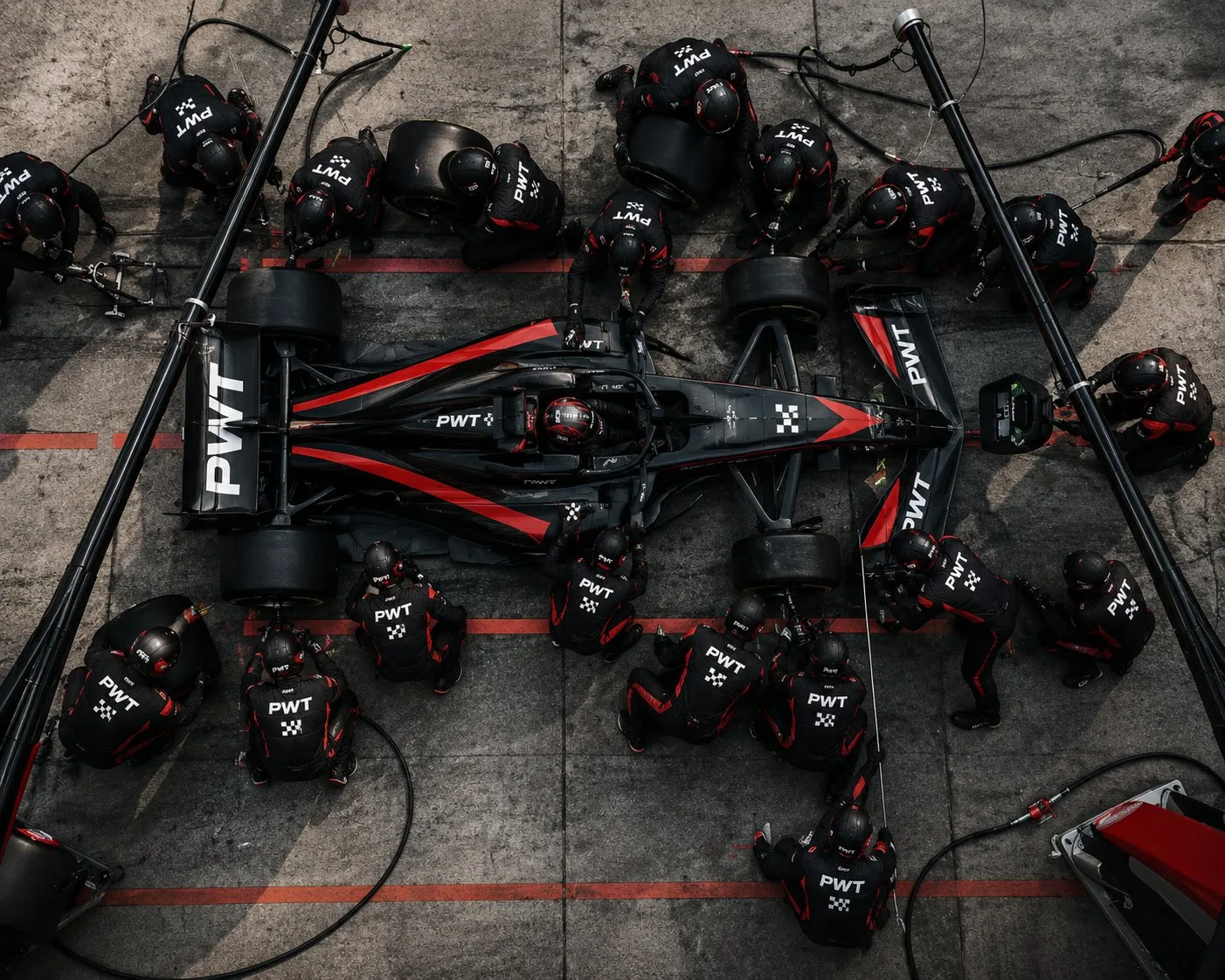Overhead view of a PWT pit crew working on the car during a stop, every position covered at once.