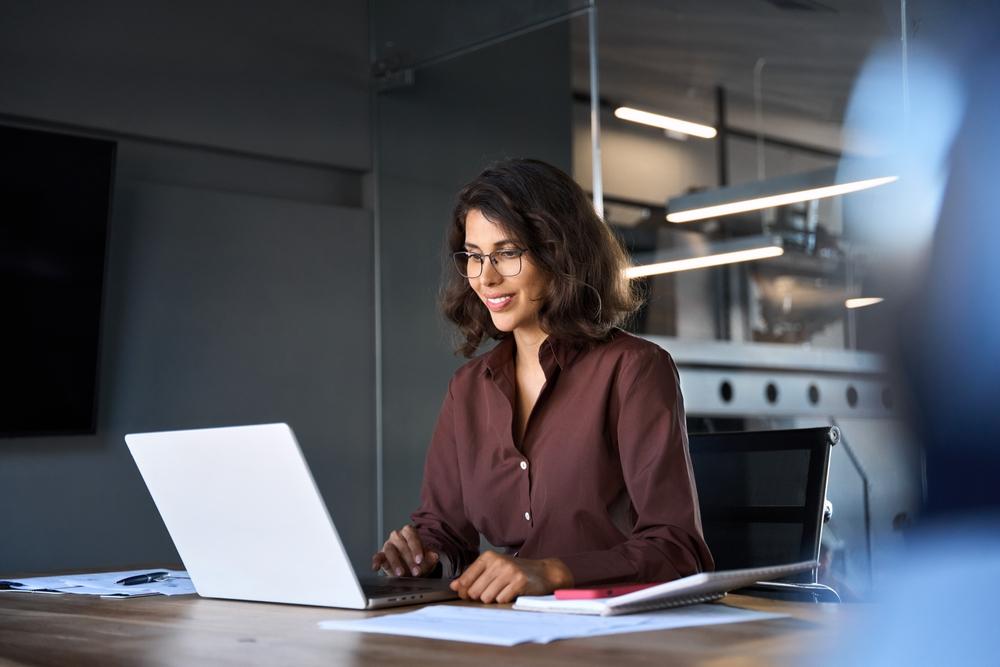 A smiling businesswoman sitting at a laptop