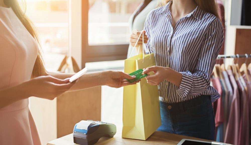 A woman handing a credit card to a sales clerk.