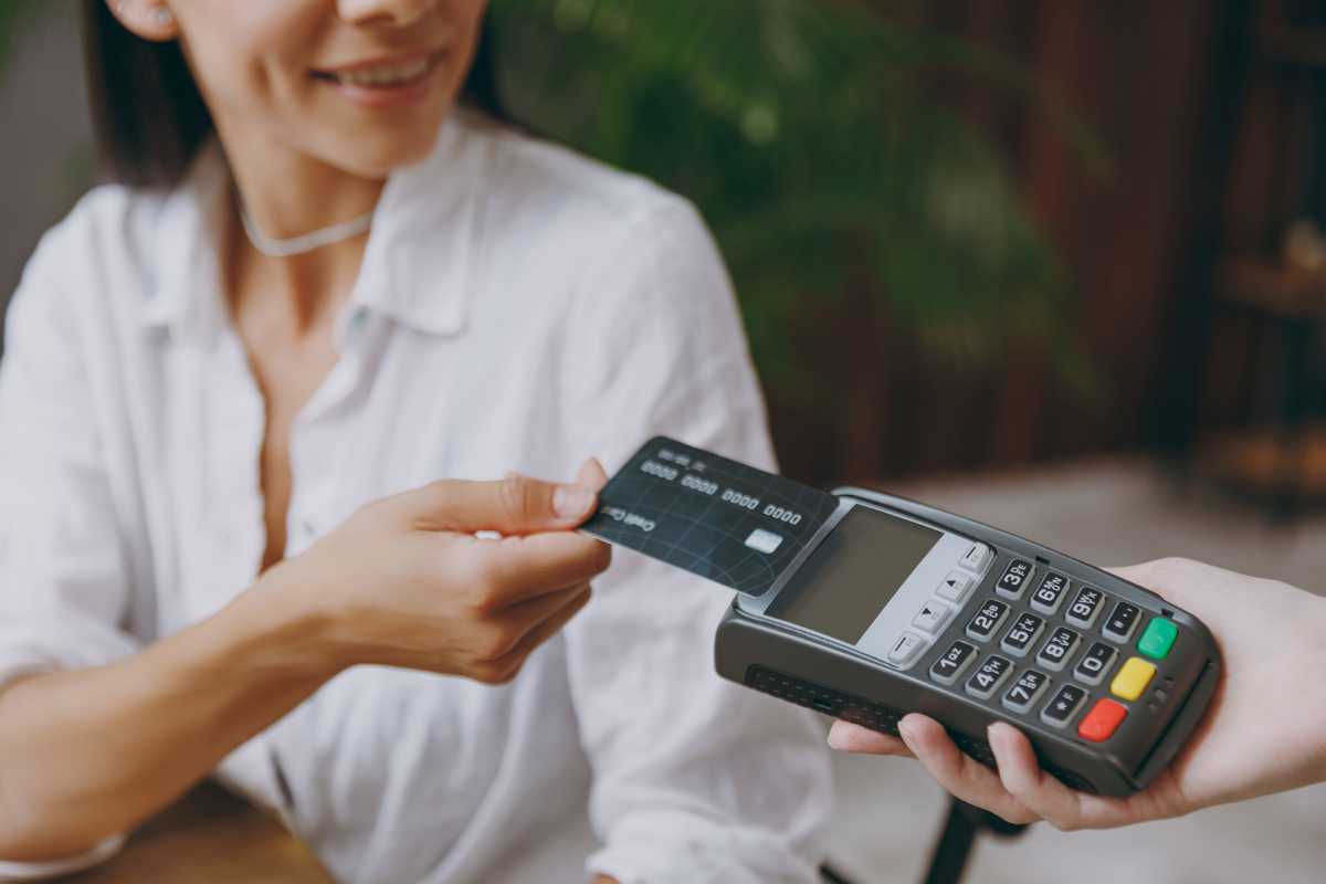 A customer taps a card to pay while seated in a cafe
