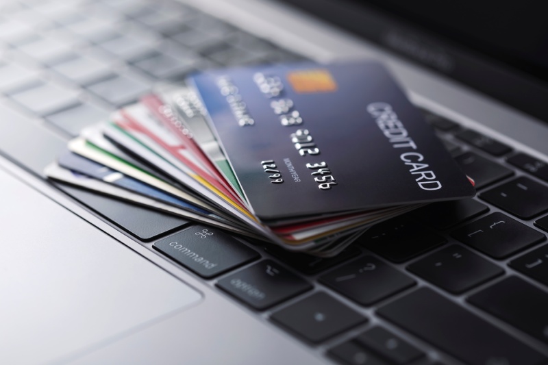 A fanned stack of credit cards sits on a laptop computer keyboard.