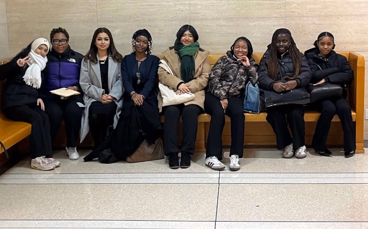Students and staff seated together on a bench during a field trip