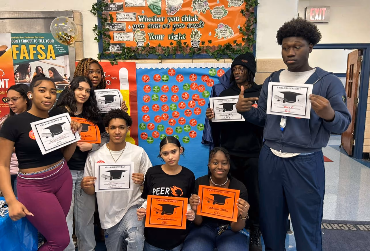 Students holding I Will Graduate Day certificates in school hallway