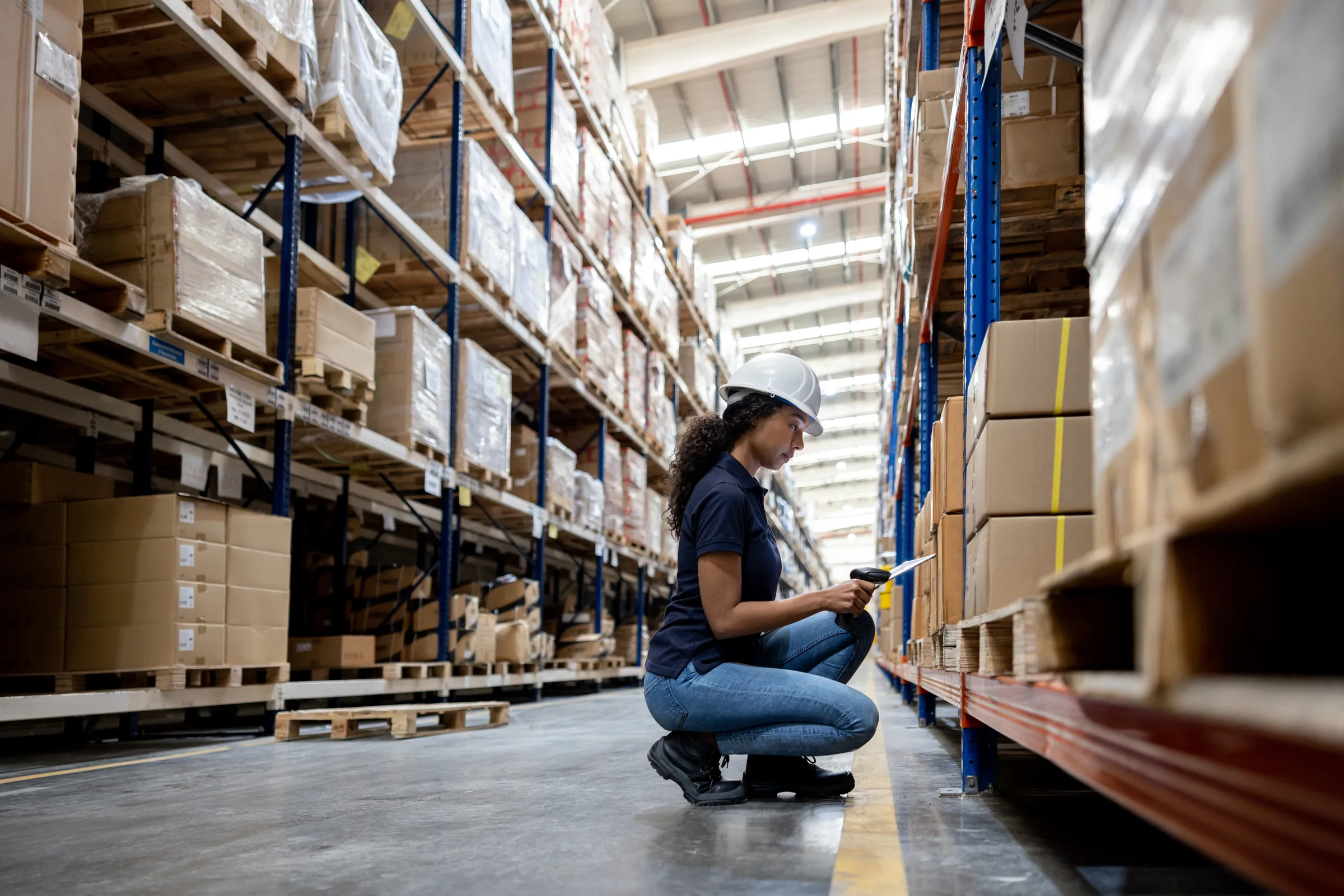 Warehouse operator counting inventory at a low shelf