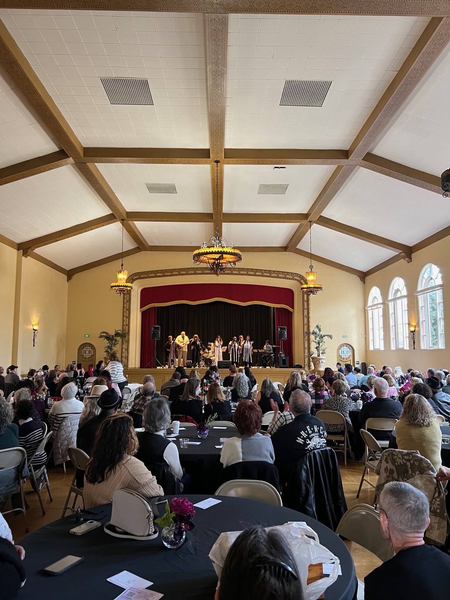 A full audience at round tables watches the band on stage at Girls Got the Blues