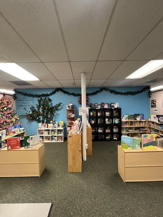A room set up with shelves of children's books and holiday decorations for Winter Open House