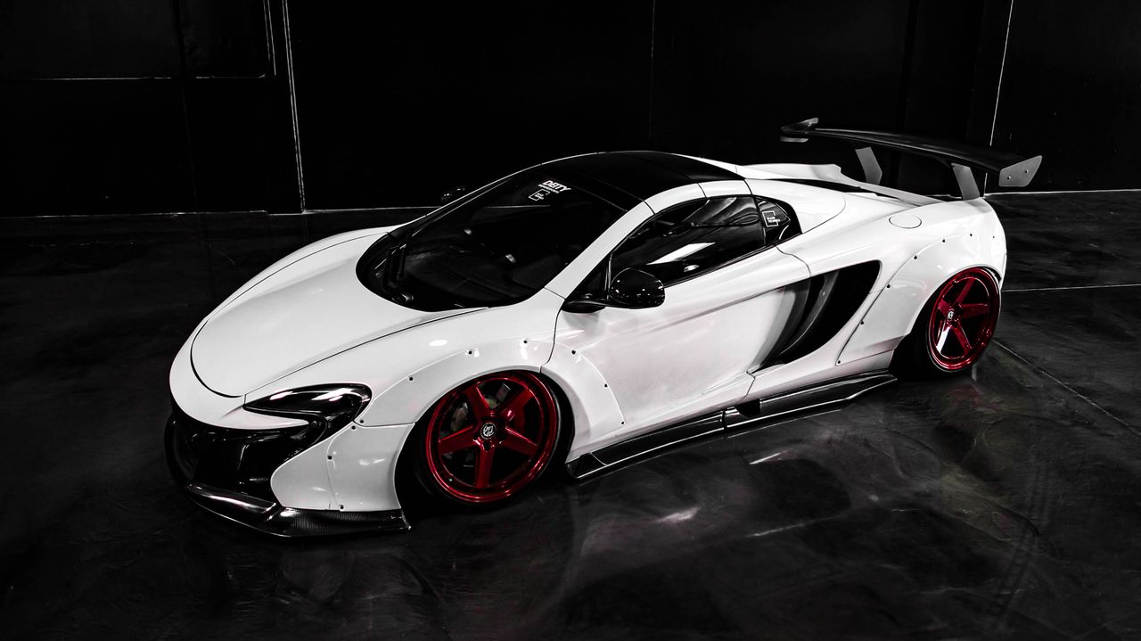 White sports car with red wheels in a dark studio