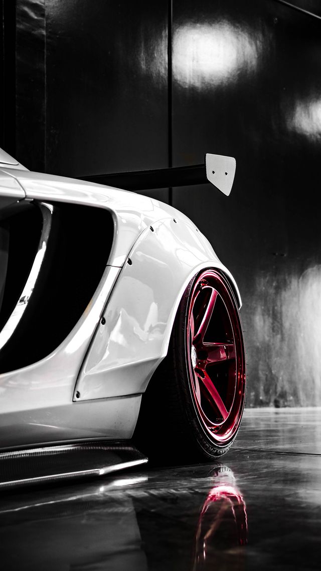 Close-up of a white sports car's rear bodywork and red wheel