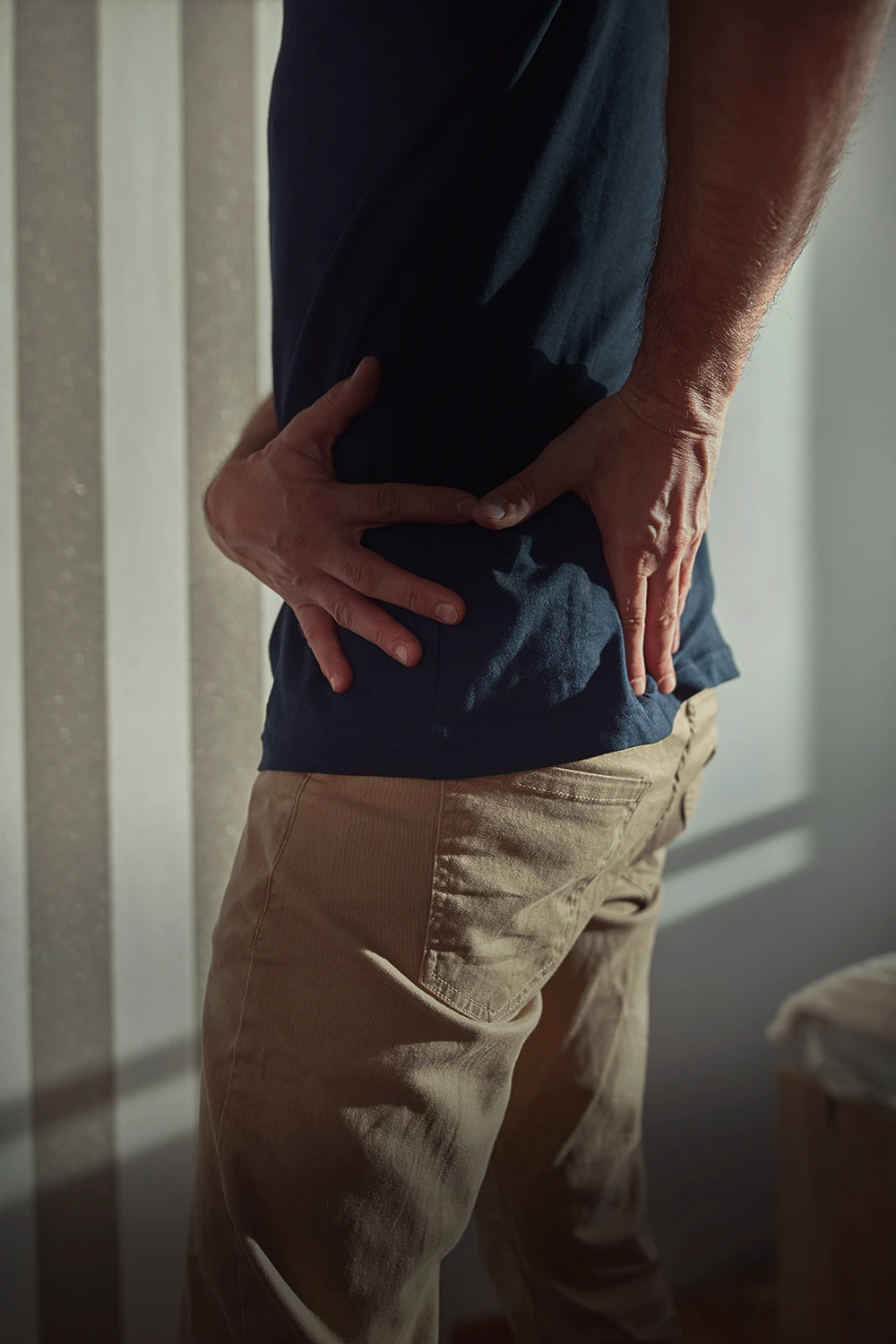 Man experiencing lower back pain after a car accident, a common injury handled by a Rego Park crash injury attorney