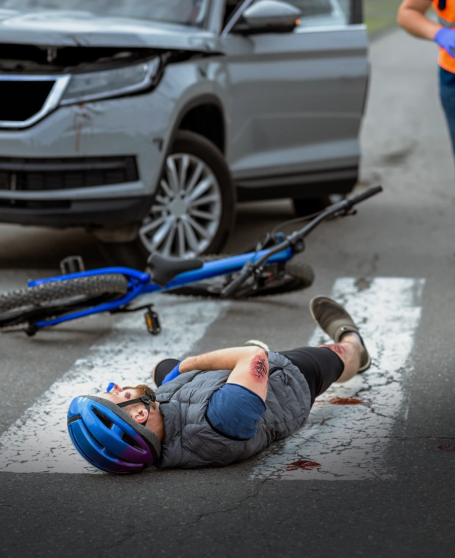 Cyclist lying injured beside a damaged bicycle after being struck in traffic days before before speaking with a Rego Park cyclist accident attorney