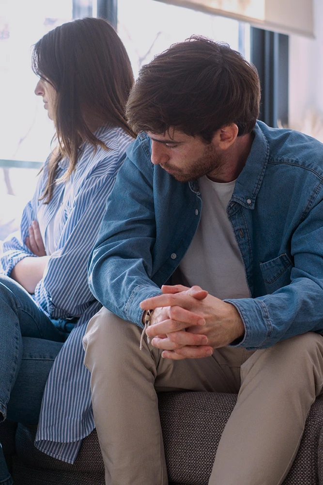 Couple sitting apart during a difficult divorce discussion after proposed terms raise new concerns, leading one spouse to seek guidance from an uncontested divorce lawyer in Rego Park, Queens