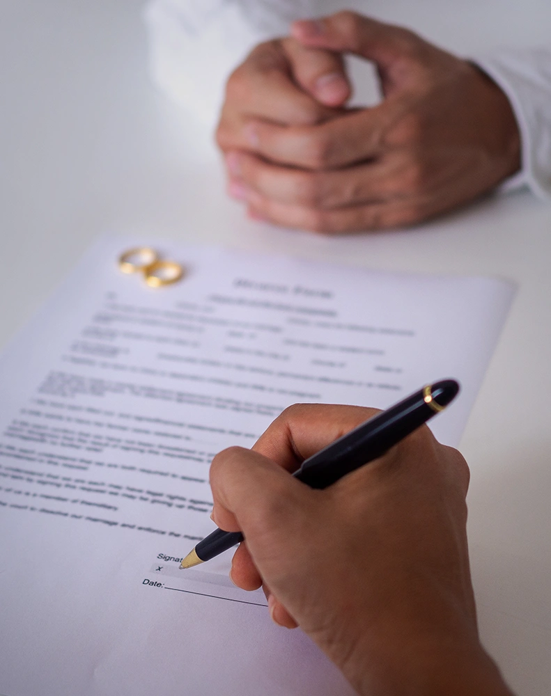 Person signing a prenuptial agreement before marriage with guidance from a prenuptial agreement attorney in Rego Park, Queens
